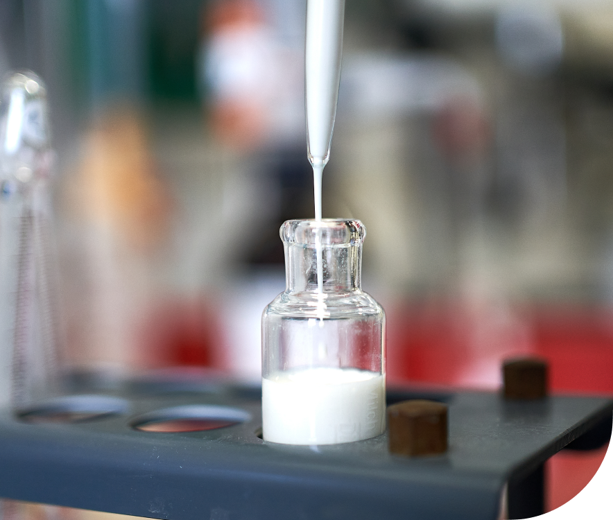 Milch-Pipettierung Glasflasche wird im Labor über Pipette mit Milchgetraenk gefuellt