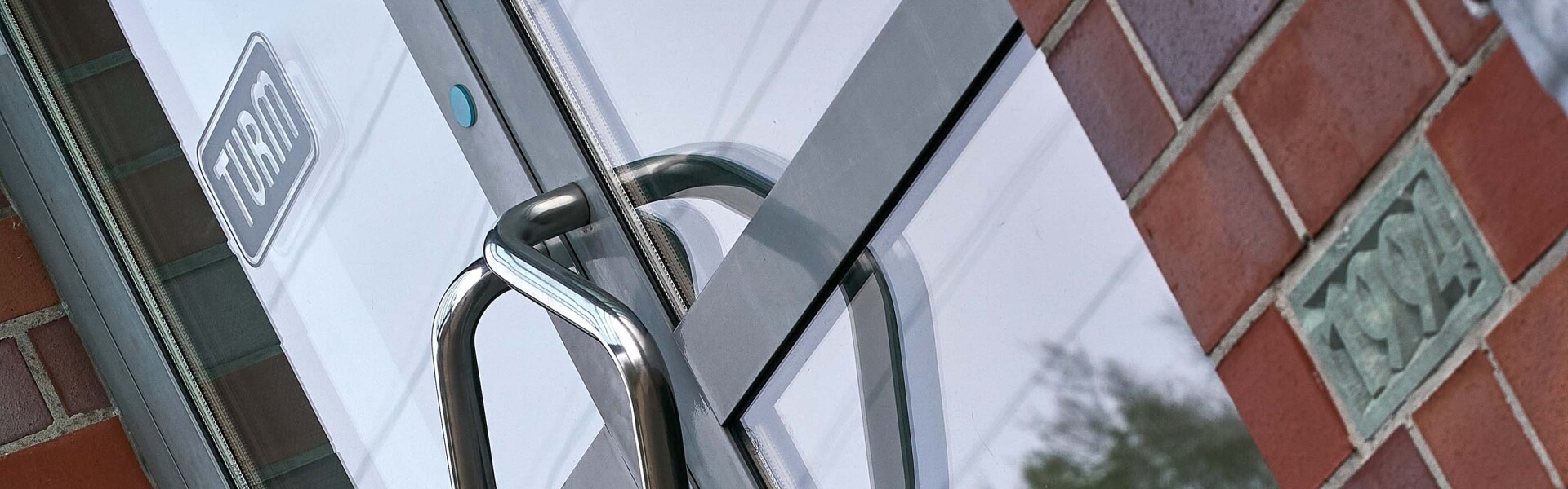 Nahaufnahme Eingangstuer aus Glas mit TURM-Logo