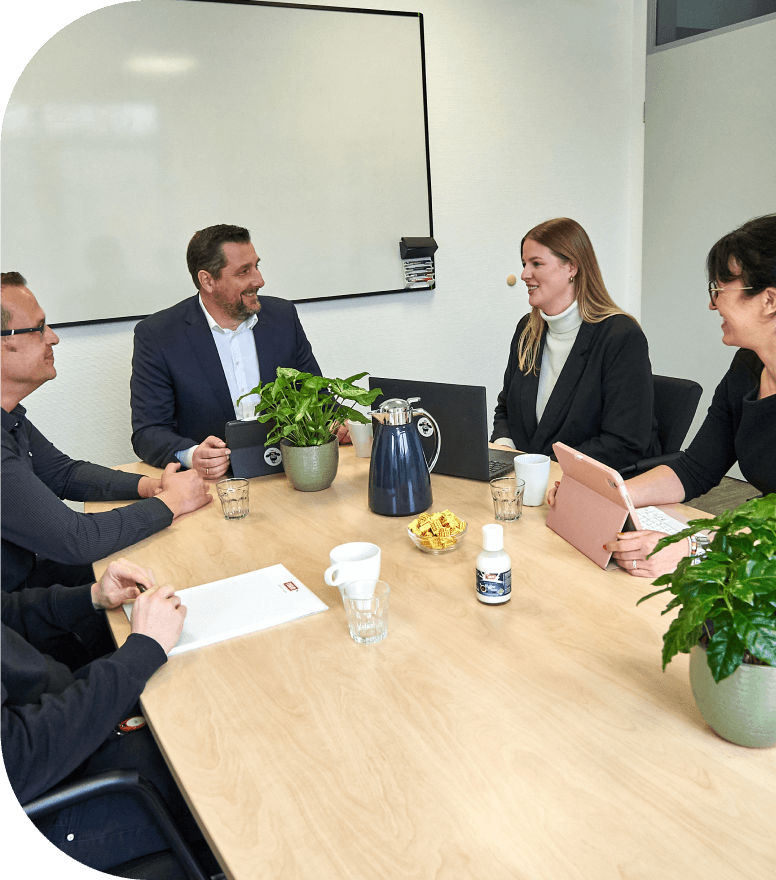 Heller Besprechungsraum, MitarbeiterInnen am Konferenztisch gedeckt mit Kaffee und Pflanzen